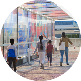 A family is bathed in colors as they walk under an artwork by Teresita Fernández at the Olympic Sculpture Park.