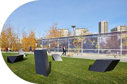 People walk past art by Tony Smith and Teresita Fernández at Olympic Sculpture Park with the Space Needle in the background.