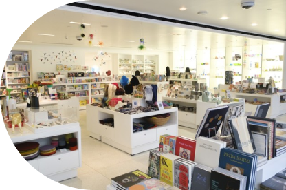 A brightly lit museum gift shop with various items on display, including books, ceramics, jewelry, and toys. The space has a clean and modern design.